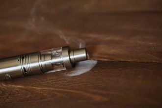 Cigarette électronique posée sur une table en bois avec de la fumée
