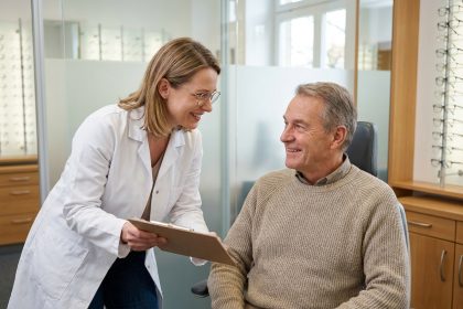 Opticienne discutant du suivi de la vue avec un patient âgé dans une salle de consultation moderne
